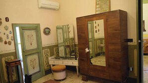 Quarto com guarda-roupa de madeira, toucador com espelho e um pequeno banquinho.