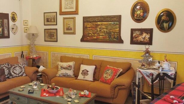 Uma sala de estar acolhedora com dois sofás, uma mesa de centro e uma mesa de jantar posta com decorações festivas.