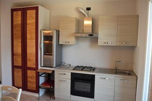 Eine kompakte Küche mit Kühlschrank, Herd, Backofen und Spüle.