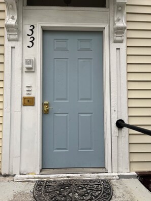 Une porte avec une poignée de porte en laiton et une boîte aux lettres fixée au mur.