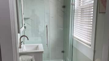 A modern bathroom with a glass-enclosed shower, a toilet, and a sink.