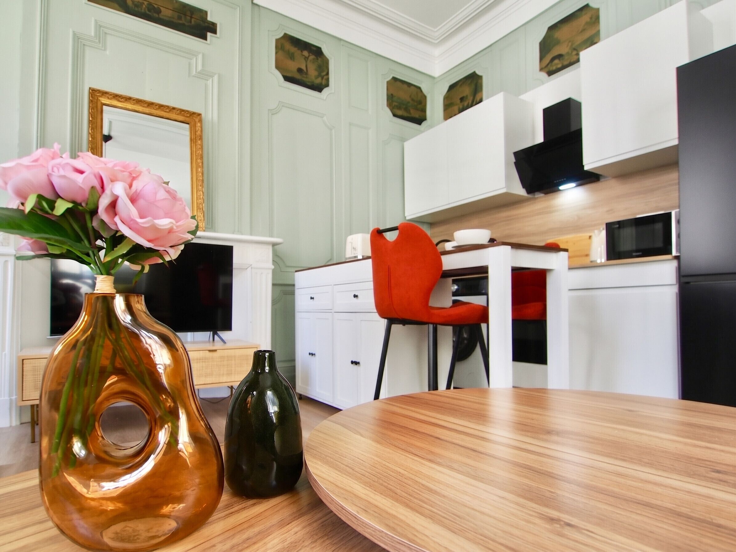 Ein Essbereich mit einem Holztisch, einer Blumenvase und einem roten Stuhl.
