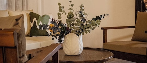 Un salón con una mesa de centro redonda de mimbre, un sofá y un cuadro en la pared.