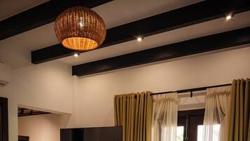 A hotel room with a bed, a television, curtains, and a ceiling light fixture.