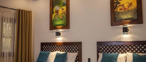 A hotel room with two beds, a wooden headboard, a painting, a lamp, and a window with curtains.