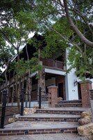 A two-story building with a stone facade, a wooden balcony, and a stone staircase leading to the entrance.