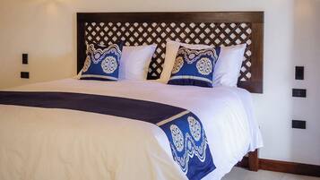 A hotel room with a large bed, two paintings on the wall, and a wooden headboard.
