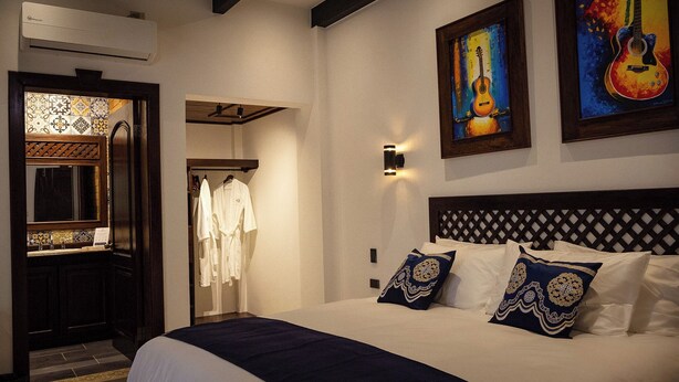 Una habitación de hotel con una cama, un armario, un espejo y dos cuadros en la pared.