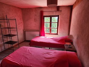 A room with two beds, a radiator, a window with curtains, and a metal shelf unit. - Secluded vacation rental with a pool in the heart of the Corbières – Nature & Relaxation (Lairière)