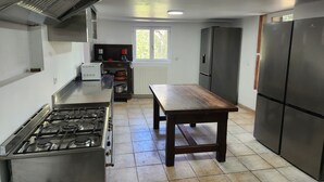 A kitchen with a gas stove, a wooden table, and a refrigerator. - Secluded vacation rental with a pool in the heart of the Corbières – Nature & Relaxation (Lairière)