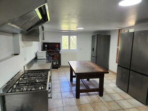 A kitchen with a gas stove, a wooden table, and a refrigerator. - Secluded vacation rental with a pool in the heart of the Corbières – Nature & Relaxation (Lairière)