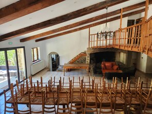 A spacious room with a high ceiling, wooden beams, a stone fireplace, and a balcony overlooking greenery. - Secluded vacation rental with a pool in the heart of the Corbières – Nature & Relaxation (Lairière)
