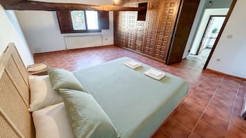 Un dormitori amb llit, almoines, radiador i armari.