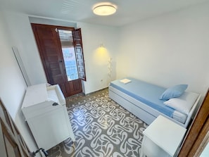 A small, compact room with a bed, a desk, and a wardrobe.