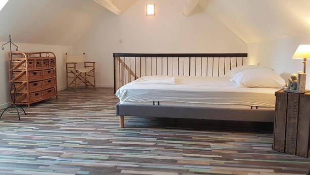 Ein Schlafzimmer mit einem Bett, Holzboden, einem kleinen Tisch und einem Sessel.