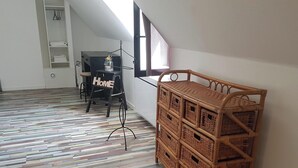 Ein Zimmer mit einem Fischgrätparkettboden, einem Korbspeicher, einem Schild mit der Aufschrift 'Home' und einem Fenster mit Jalousien.
