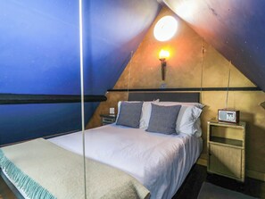 Ein Schlafzimmer mit einem Bett, Kissen, einem Nachttisch, einer Lampe und einem Radio.