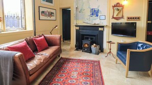 A living room with a leather sofa, a patterned rug, a fireplace, a television, and a map on the wall. - The Sunday School Room (Sherborne)