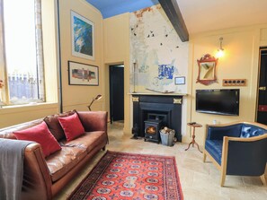 Ein Wohnzimmer mit Ledersofa, einem gemusterten Teppich, einem Kamin, einem Fernseher und einer Karte an der Wand.