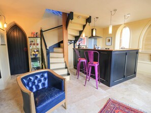 Ein modernes Interieur mit Barbereich, einer Treppe und einer Sitzecke mit blauem Sessel.