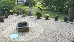 En udendørs terrasse med pejse, siddepladser og plantekasser.