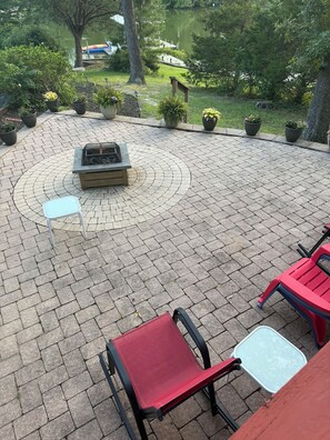 An outdoor patio with a fire pit, seating, and potted plants. - Cozy Creekside Cottage – AC, Dock, Kayaks & Firepit (Deltaville,)