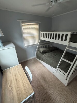 A room with a bunk bed, a desk, a chair, a window with blinds, and a ceiling fan. - Cozy Creekside Cottage – AC, Dock, Kayaks & Firepit (Deltaville,)