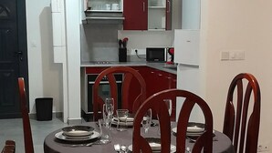 Un comedor con una mesa redonda, cuatro sillas de madera y un ventilador de techo.