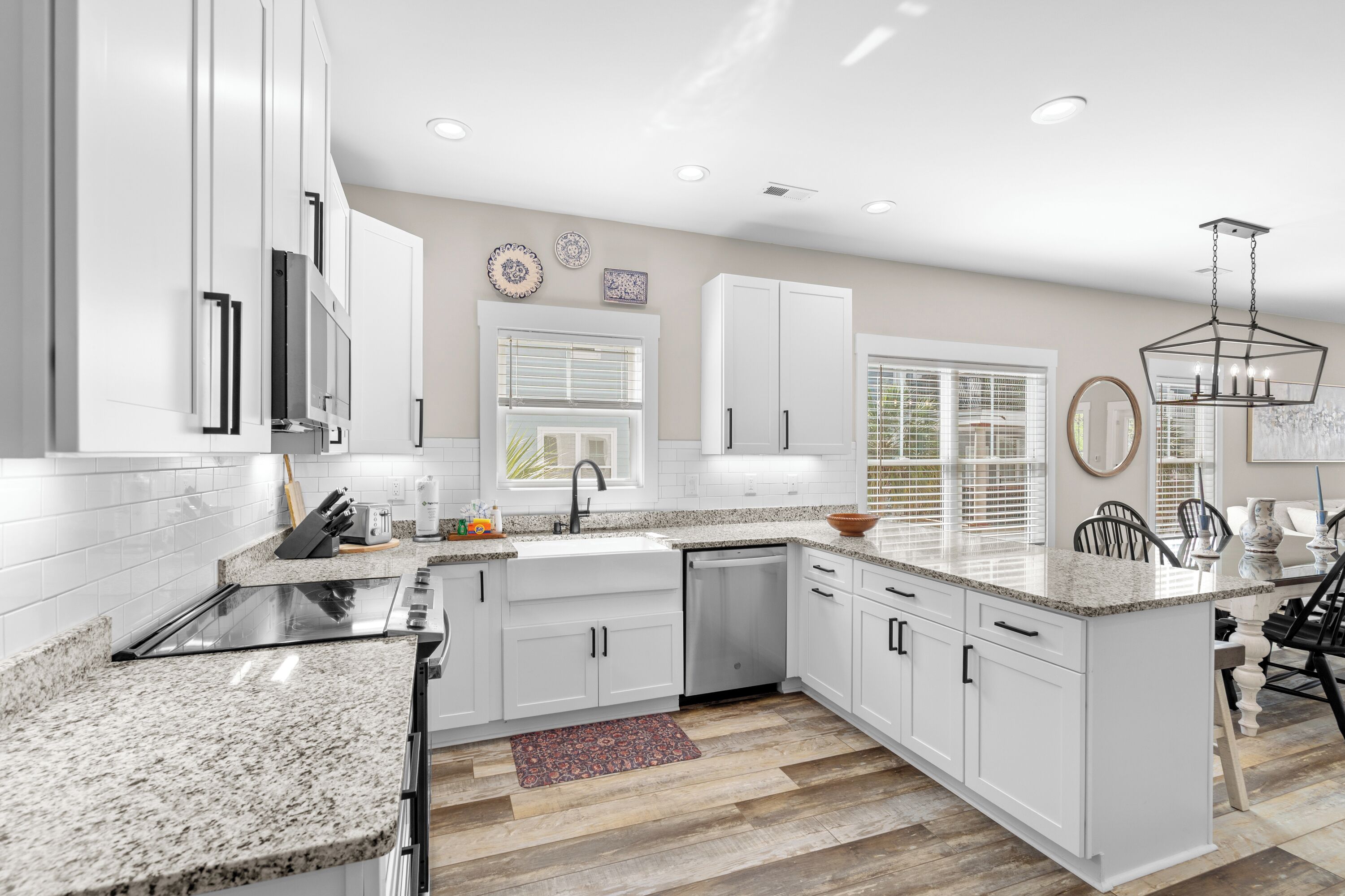 A modern kitchen with white cabinets, granite countertops, a built-in dishwasher, and a large island with seating.