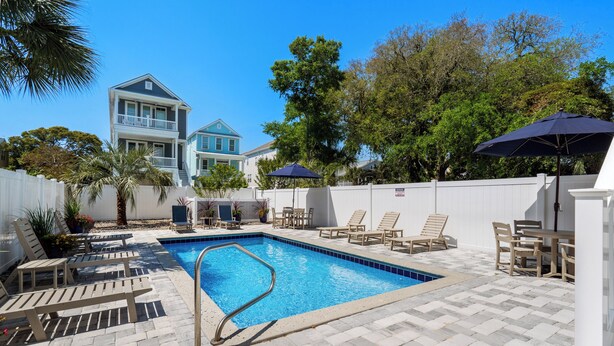 A swimming pool with a metal safety railing, surrounded by lounge chairs and umbrellas. - Private Pool House — 5BR/5BA in Surfside Beach, Steps to the Beach (Surfside Beach)