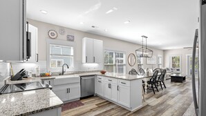 A modern kitchen with white cabinetry, granite countertops, and a central island. - Private Pool House — 5BR/5BA in Surfside Beach, Steps to the Beach (Surfside Beach)