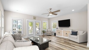 A spacious living room with a sofa, coffee table, and a television mounted on the wall. - Private Pool House — 5BR/5BA in Surfside Beach, Steps to the Beach (Surfside Beach)