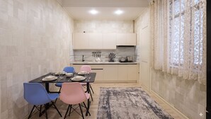 A compact kitchen with modern appliances, a dining table set for four, and a patterned rug. - Fabulous 2-bedroom apartment with AC in charming Toshkent (Тоshkent)
