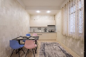 A compact kitchen with modern appliances, a dining table set for four, and a patterned rug. - Fabulous 2-bedroom apartment with AC in charming Toshkent (Тоshkent)