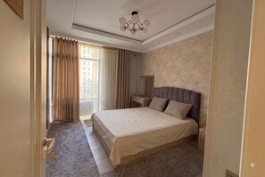 Ein Hotelzimmer mit einem großen Bett, einem Nachttisch, einem Spiegel und einem Fenster mit Vorhängen.
