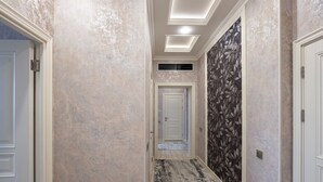 A hallway with textured walls, a patterned carpet, and a door at the end. - Fabulous 2-bedroom apartment with AC in charming Toshkent (Тоshkent)