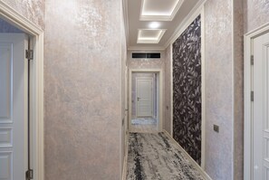 A hallway with textured walls, a patterned carpet, and a door at the end. - Fabulous 2-bedroom apartment with AC in charming Toshkent (Тоshkent)