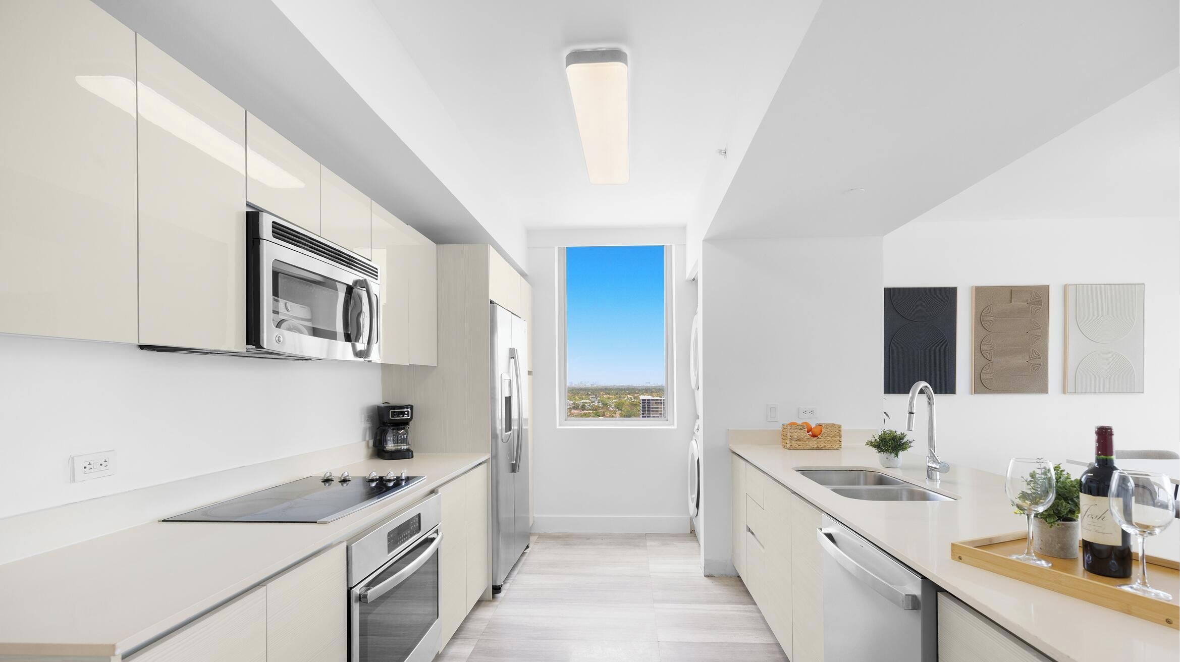 A modern kitchen with stainless steel appliances, a window with a city view, and minimalist decor.