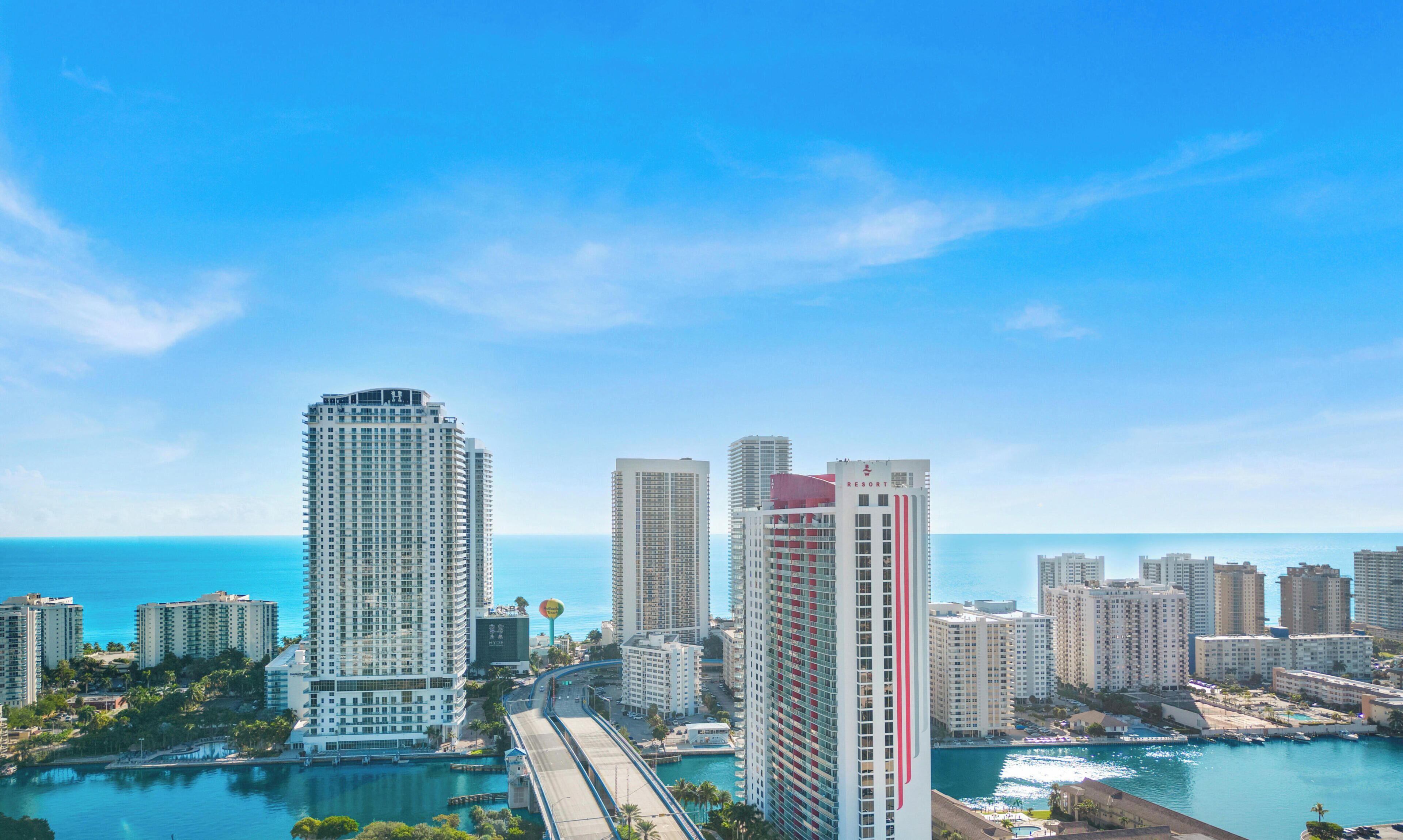 A high-rise hotel with a view of the ocean, a marina, and a bridge.