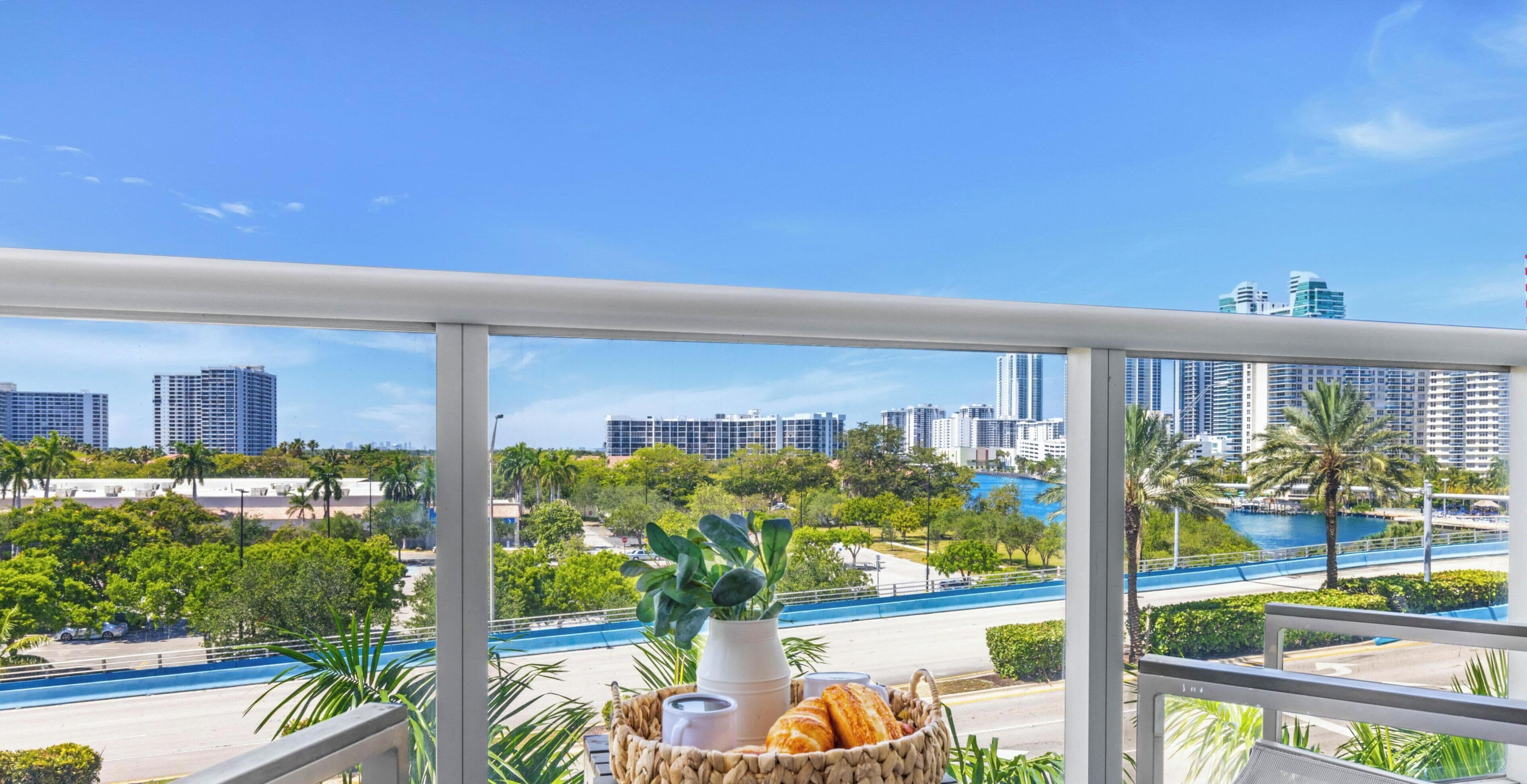A balcony with a view of a cityscape, a road, and a body of water.