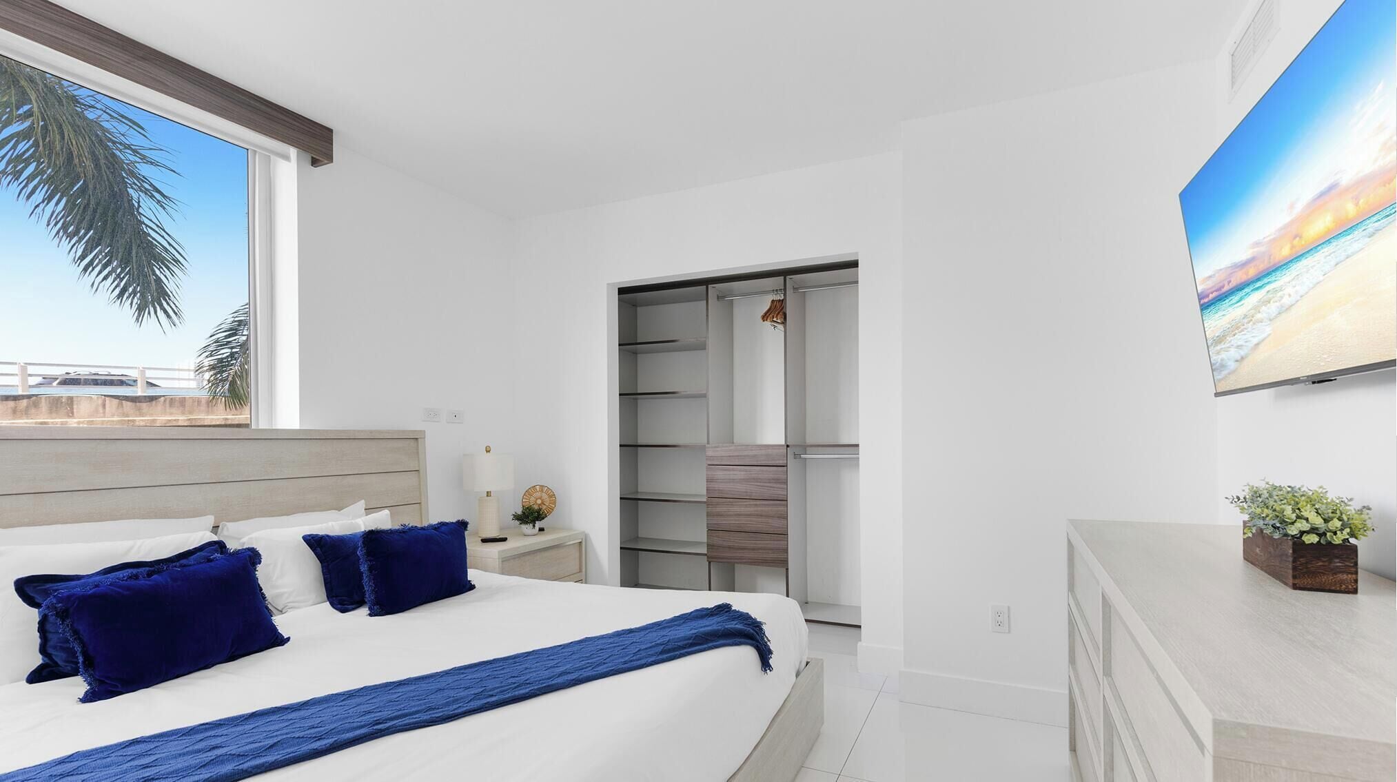 A modern bedroom with a bed, bedside table, and a view of the outside.