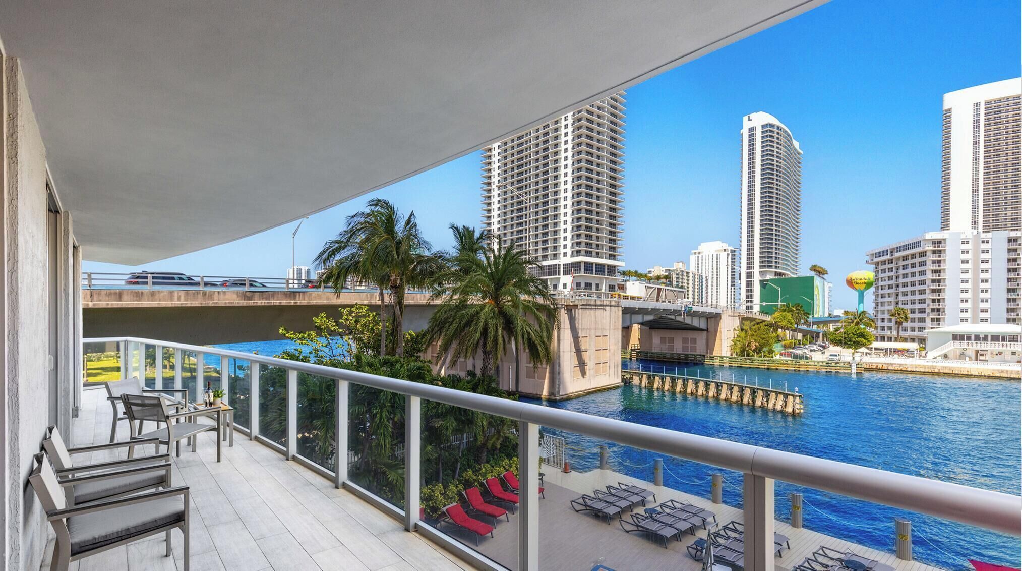 Un balcon avec vue sur une marina, des palmiers et des immeubles de grande hauteur.