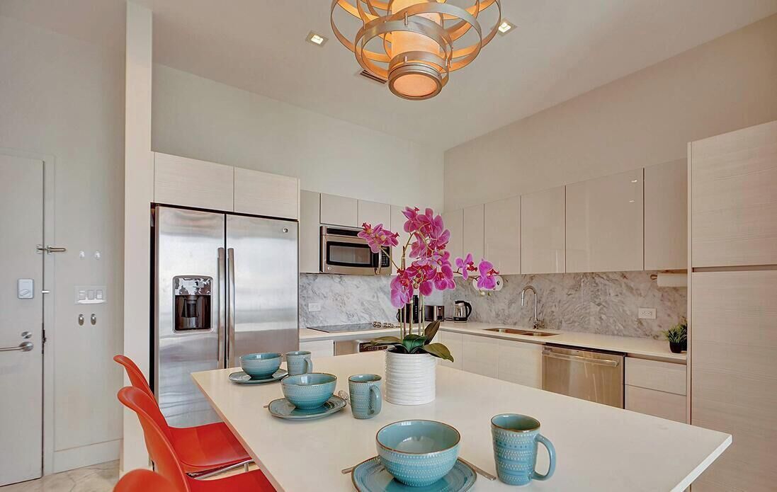 A modern kitchen with a central island, stainless steel appliances, and a decorative orchid centerpiece.