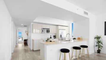 Una cocina moderna con una isla central, taburetes de bar y vistas al exterior.