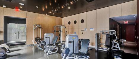 Un gimnasio moderno con diversas máquinas de ejercicio, paredes de madera y suelo pulido.
