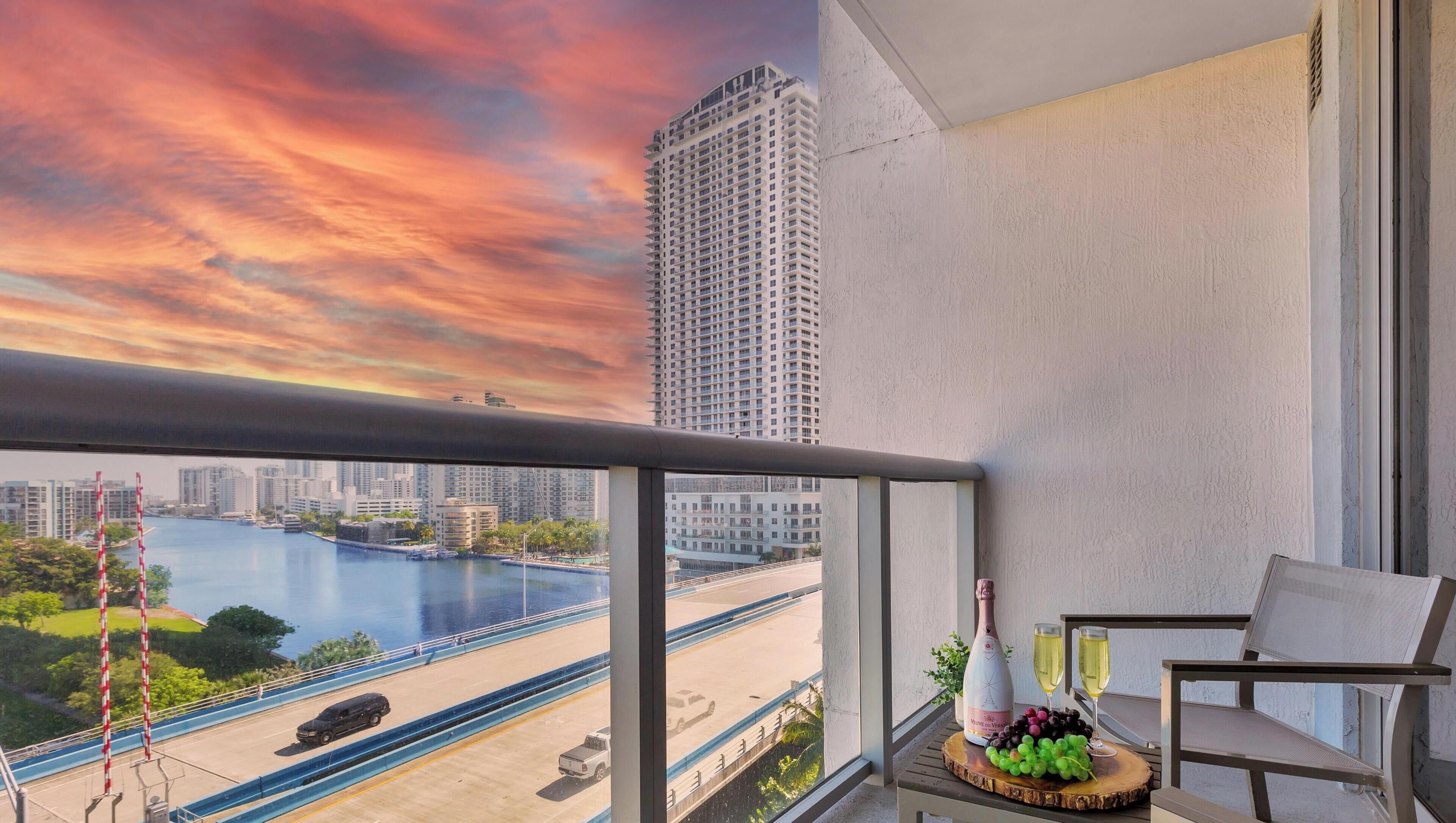 A balcony with a view of a river, a high-rise building, and a cityscape.