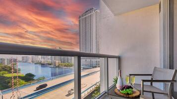 A balcony with a view of a river, a high-rise building, and a cityscape.