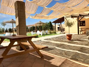 Ein Außenbereich mit einer Holzterrasse, einem Grill und einer Pergola mit Stoffbeschattung.