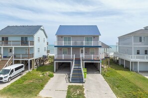 Una propiedad frente a la playa con un edificio central que tiene techo azul, un paseo cubierto y un garaje.