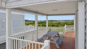 En overdækket terrasse med et picnicbord og hvide gelændere.